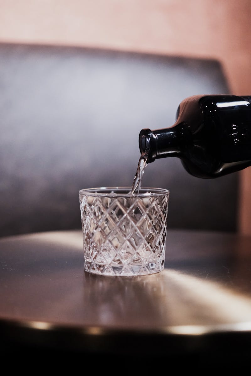 A bottle of vodka being poured into a crystal glass, symbolizing the struggle with alcoholism faced by the main character in 365 Days of Becoming.